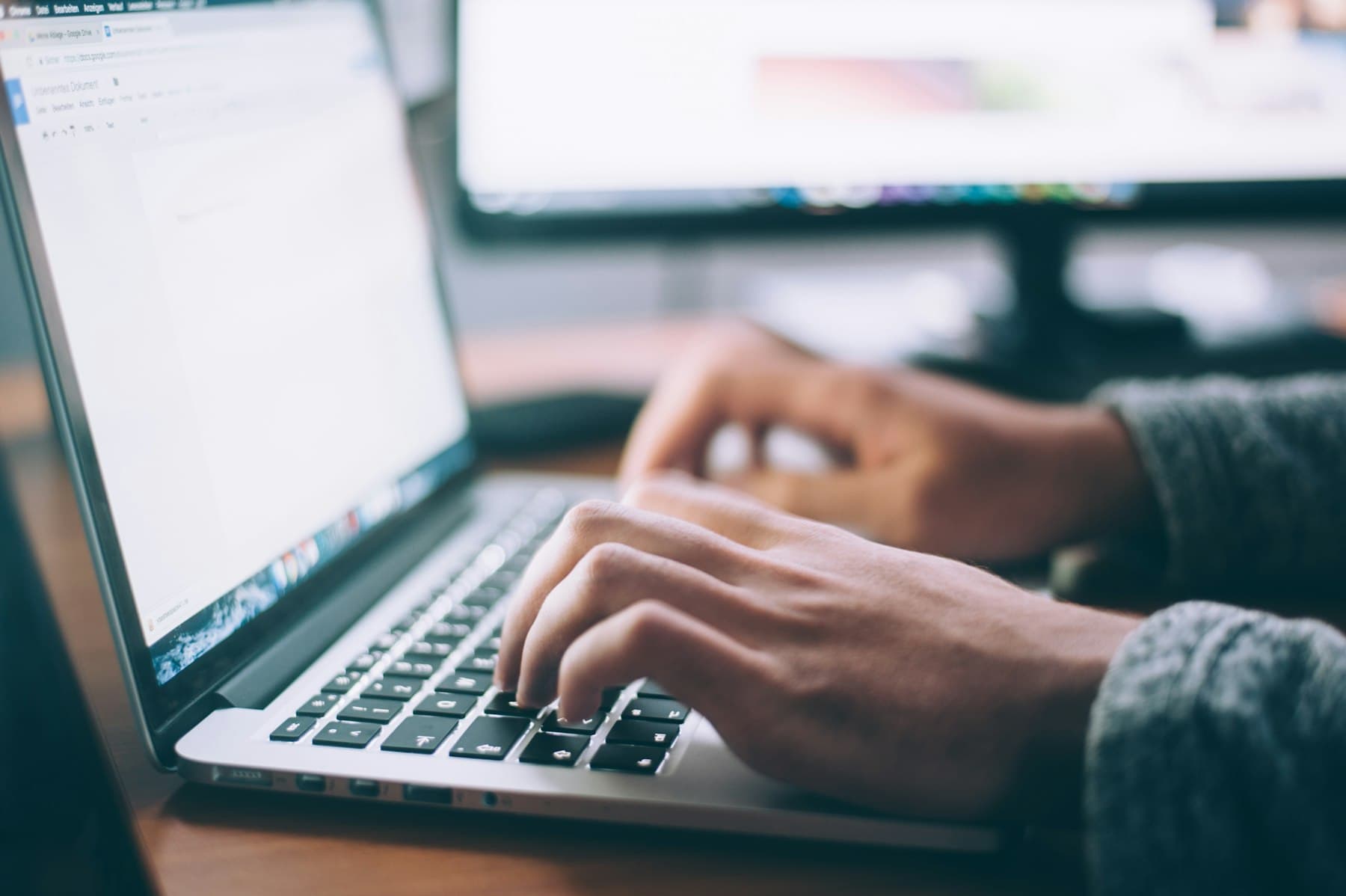 A laptop open on a wooden desk in morning light